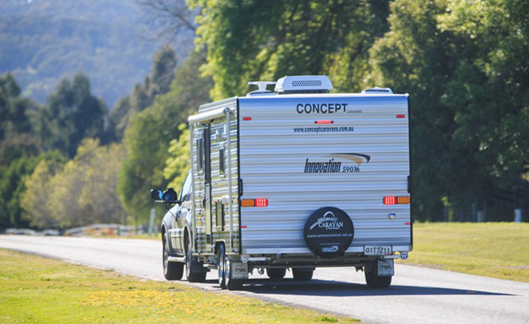A car is towing an Concept Innovation caravan on the street